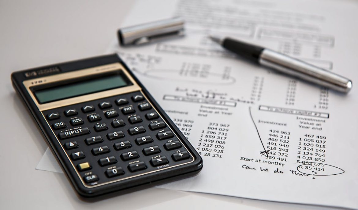 A calculator, pen, and a piece of paper on a white surface